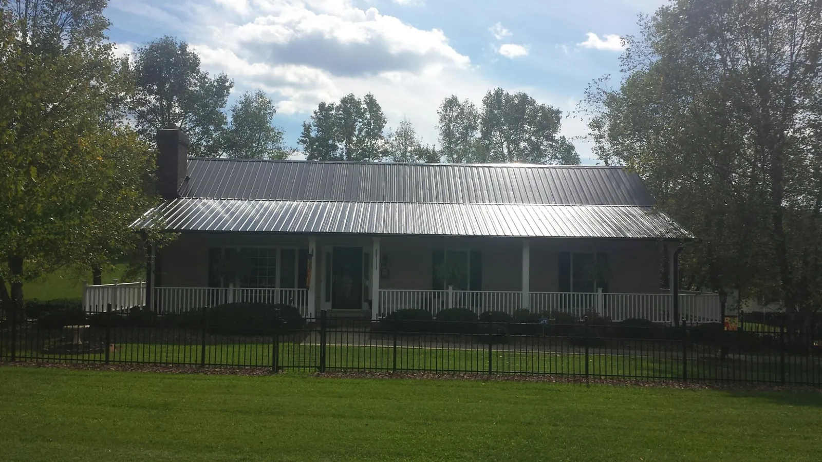 Gray metal roof on a brick ranch with a full width front porch — Gutter Guard Installation work by our crew in Mchenry